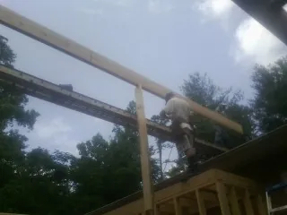 Carpenter setting a ridge beam over a new addition frame — Ice Dam Removal by Roofing Brothers in Saint Francis