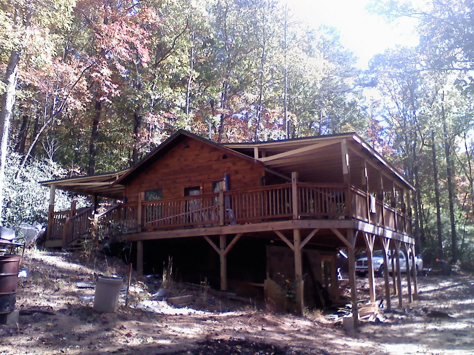 Log cabin with a wraparound porch and metal roof in the fall in Saint Francis