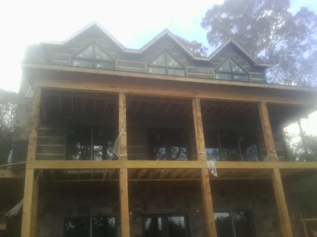 Dormers and porch framing on a large log home under construction — Roof Coating work by our crew in Saint Francis