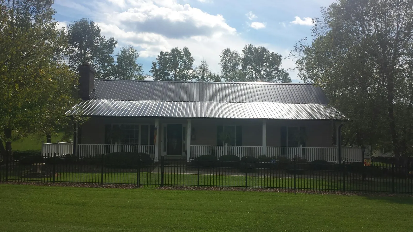Gray metal roof on a brick ranch with a full width front porch — Gutter Guard Installation work by our crew in Saint Francis